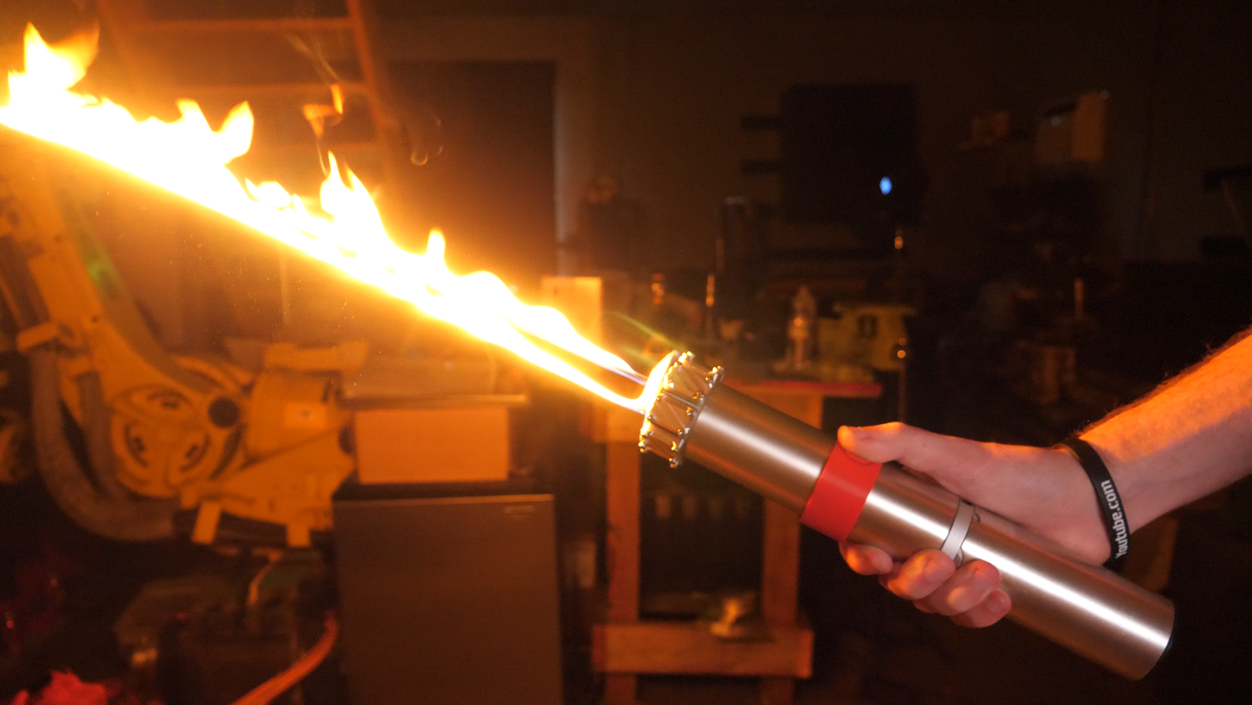 Person holding a flamethrower in a workshop setting
